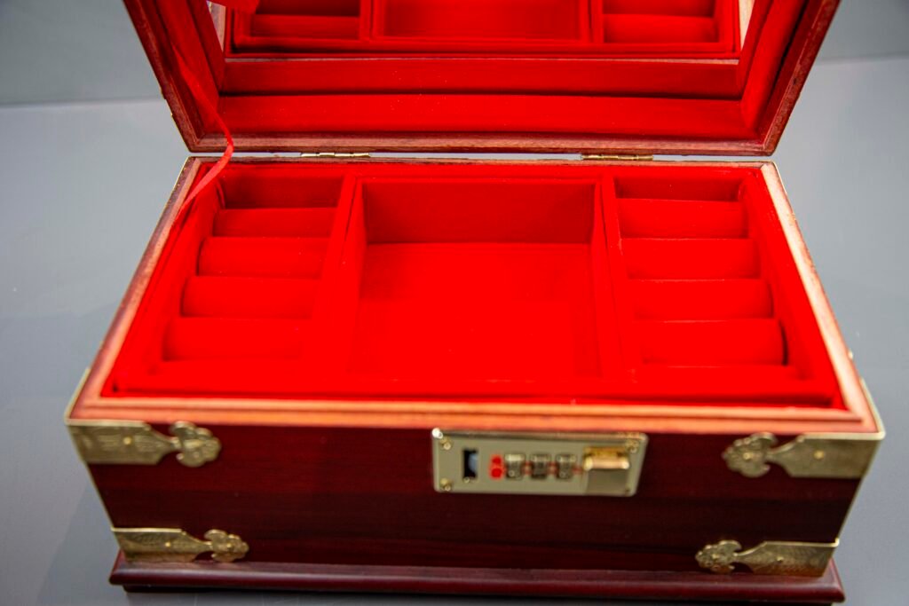 Open Chinese red velvet jewelry box with mirror and compartments Desc 1: Interior view of velvet-lined jewelry box with various storage sections